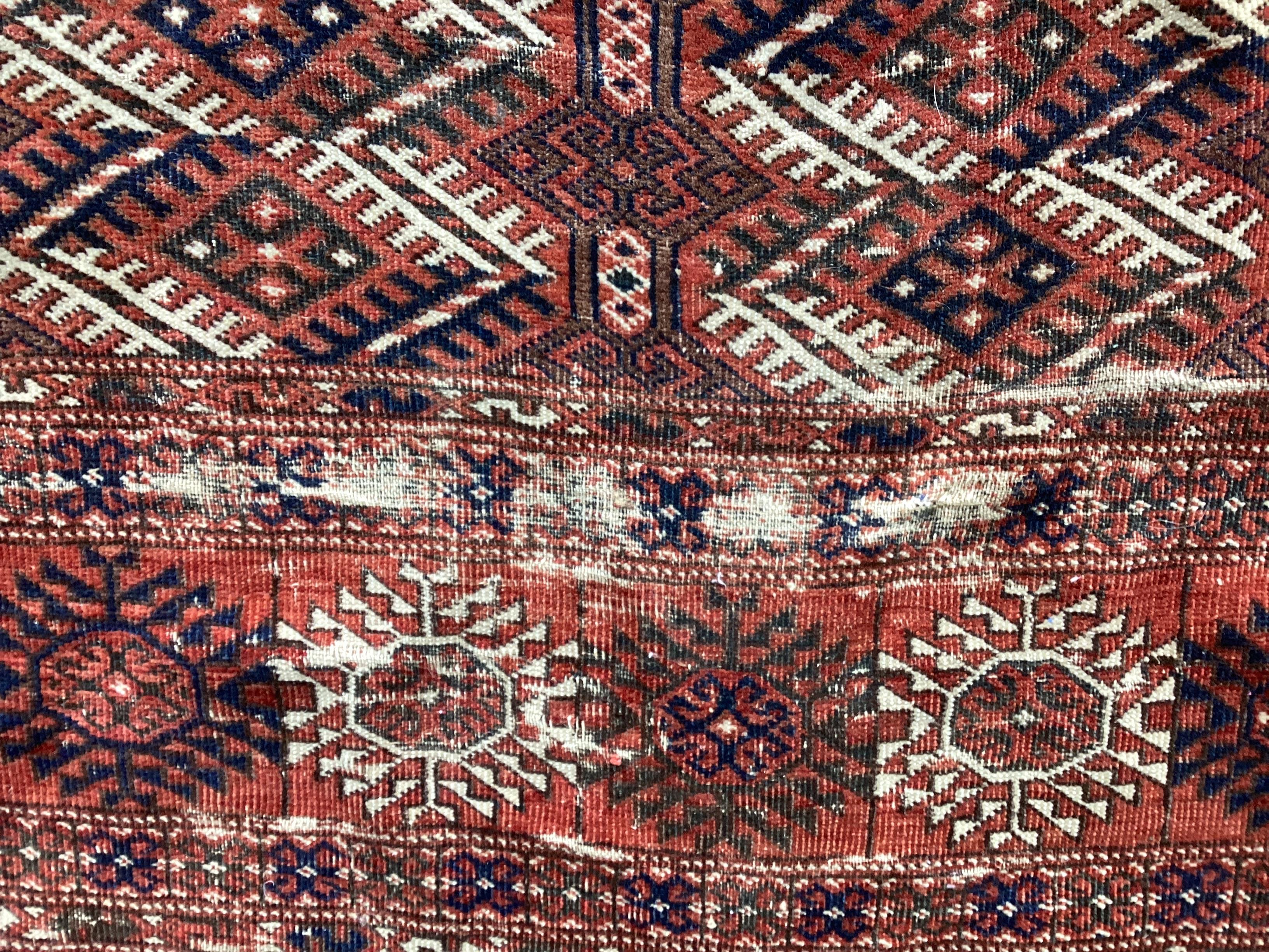 A Bokhara red ground carpet, woven with rows of elephants foot, 308 x 203cm (Worn at one end)